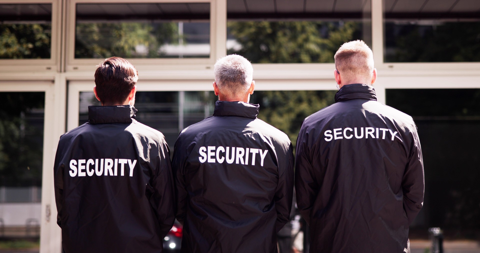 Security team of uniformed guards stand with hands clasped behind their backs